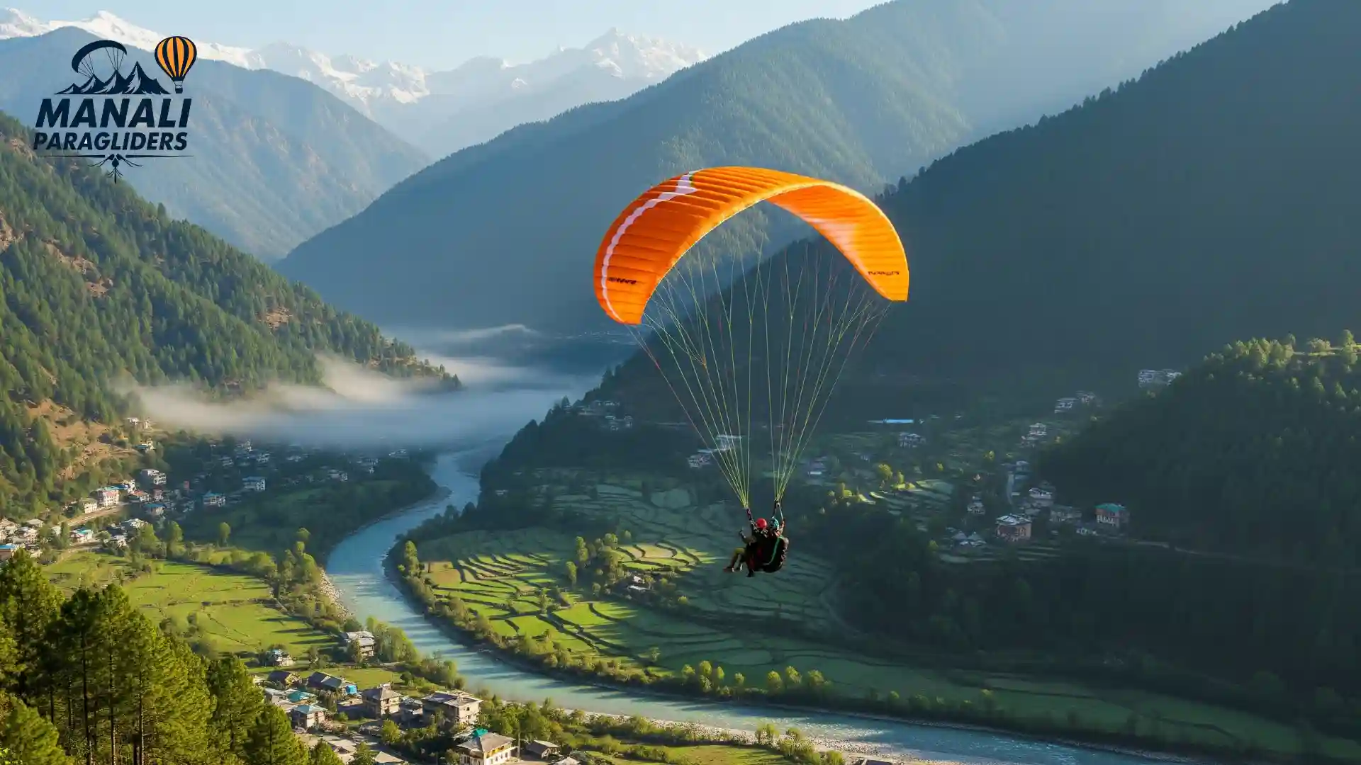 Tandem paragliding flight with Kullu Manali Paragliders over the Beas River and green valleys towards snowy Himalayan peaks.